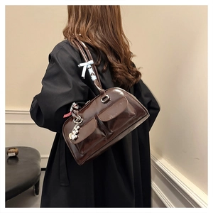 Close-up of brown patent leather bag with ribbon bow and silver heart charm details
