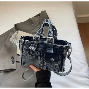 Close-up of vintage dark blue denim handbag with functional pockets and metal hardware details