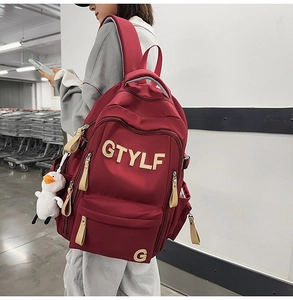 Detail of red large capacity nylon backpack with GTYLF embroidery and duck pendant