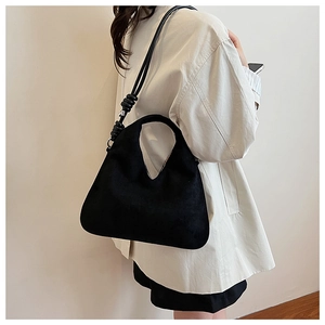 Close-up of black matte suede shoulder bag featuring unique knotted ring strap detail