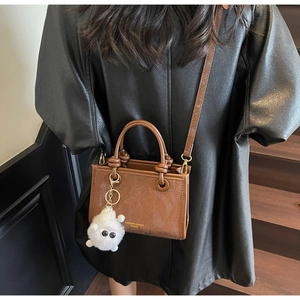 Detail of vintage brown leather bucket bag with gold lettering and plush toy charm
