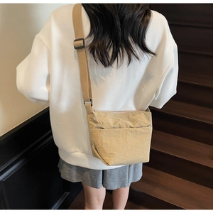 Détail du sac seau en nylon kaki clair avec bandoulière noire réglable sur modèle