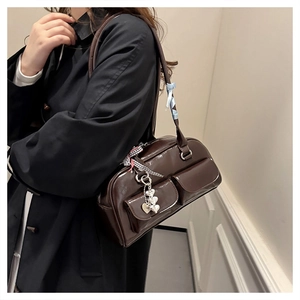 Macro shot of dark brown patent leather shoulder bag with side pockets and decorative charms