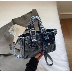 Detailed shot of dark blue denim tote bag with silver rivets and utility pocket detail