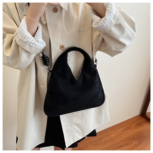 Detail of black suede hobo bag with a unique knotted strap and silver buckle