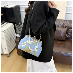 Detailed embroidery of white flowers and golden leaves on sky blue vintage crossbody bag