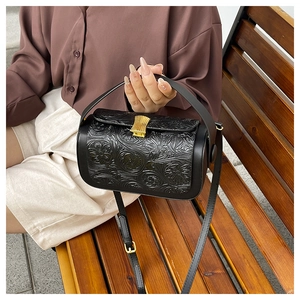 Close-up of vintage black cylinder bag with 3D floral embossing and gold clasp detail