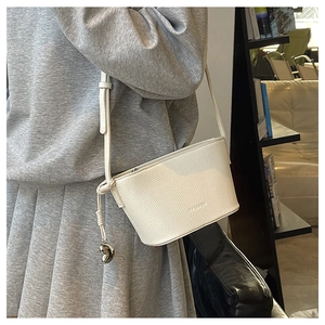 Detail of cream white pebbled leather bucket bag with silver charm and FASHION imprint