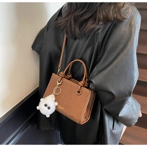 Brown leather crossbody bucket bag with metal ring and plush doll charm detail
