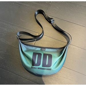 Detail of gradient green nylon crescent bag with printed letters and adjustable strap