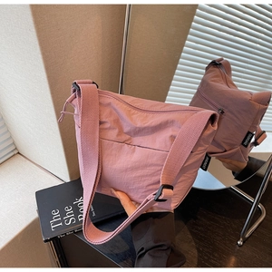 Détail du sac seau en nylon rose poudré avec bandoulière réglable et étiquette tissée