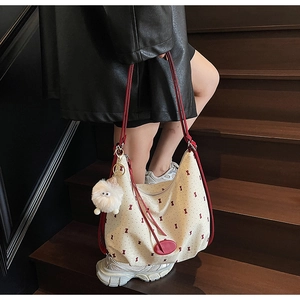 Close-up of cream canvas tote bag with red bow patterns and cute plush charms