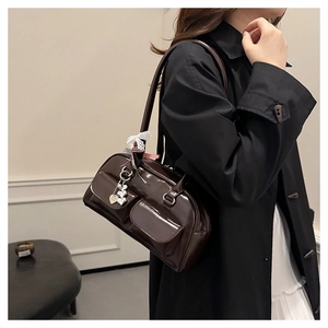 Detail of dark brown patent leather bowling bag featuring heart charms and lace bows