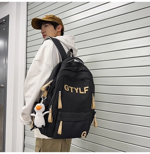 Detail of black backpack showing GTYLF logo, leather puller, and cute duck keychain