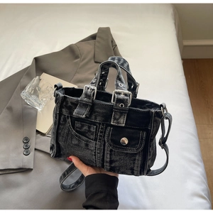 Detail of black washed denim tote bag with silver belt buckle and snap flap pockets