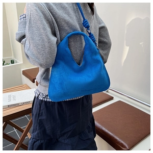 Detail of blue suede hobo bag showing the knotted shoulder strap and matte texture