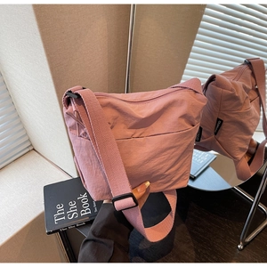 Détail du sac seau en nylon rose avec bandoulière réglable et étiquette de logo noire