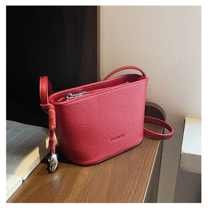 Detail of red lychee grain leather bag with heart charm and silver metal zipper