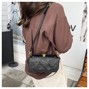 Detail of vintage black crossbody bag with embossed floral pattern and gold metal clasp