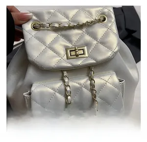Detail of golden metal twist lock and quilted faux leather texture on pearl white backpack