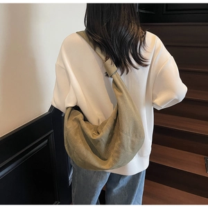 Detailed view of the large olive green canvas hobo bag worn over a model shoulder