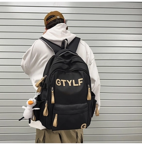 Detail of black backpack with GTYLF lettering and white duck charm on a model