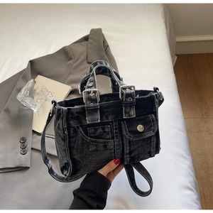 Detail of dark grey denim tote bag showing front flap pocket and adjustable metal buckle