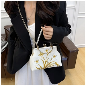 Close-up of white satin bag with gold floral embroidery and pearl handle detail
