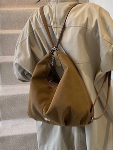 Minimalist brown suede backpack showing the texture and metal logo detail on stone stairs