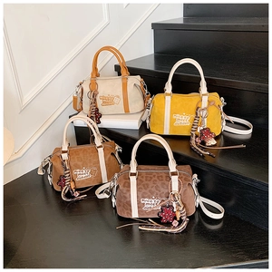 Detail of four colorful suede Boston bags with tassel charms on black stairs
