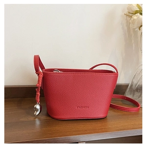 Detailed macro view of red lychee leather bucket bag with silver heart charm and strap