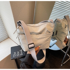 Détail du sac seau en nylon plissé beige avec double fermeture éclair et bandoulière large