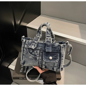 Close-up of vintage blue denim handbag with metallic buckles and adjustable shoulder strap