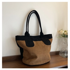 Detail view of large brown and black contrast tote bag in textured suede fabric