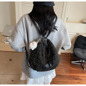 Detailed view of black gold tweed backpack on a model with plush charm and leather straps