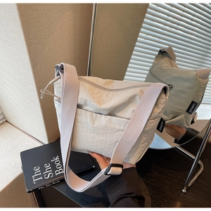 Détail du sac seau en nylon gris clair avec bandoulière réglable et reflet du miroir