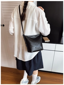 Detailed view of black woven texture bucket bag shown on model for a trendy styling