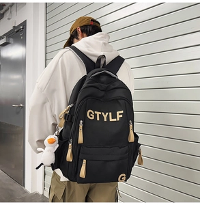 Detail view of large black nylon backpack featuring GTYLF logo and white duck pendant