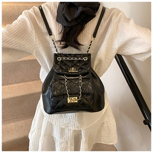 Detail of black quilted leather backpack with gold chain straps and metal twist lock