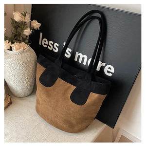Detail of a brown suede tote bag featuring black leather contrast stitching and pockets