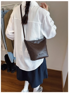 Detailed shot of dark brown woven bucket bag with fine leather texture and adjustable strap