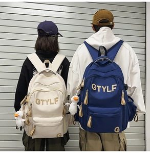 Detailed back view of off-white and navy nylon backpacks with cute duck pendants