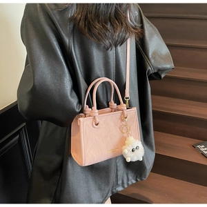 Sac seau rose plissé en similicuir avec charm mouton porté par un mannequin de mode