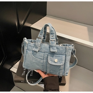 Close-up of light blue denim tote bag with silver hardware and detailed stitching