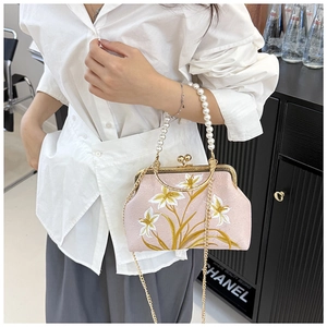 Detail of pink embroidered silk handbag with floral lily patterns and pearl handle