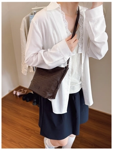 Detail of dark brown woven texture shoulder bag with leather finish and side buckle