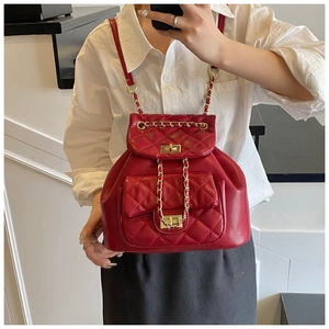 Macro detail of wine red quilted leather bucket bag with golden chain and twist lock