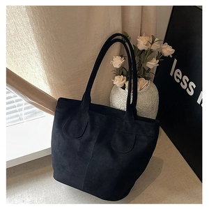 Detailed close-up of minimalist black tote bag with vertical stitching and decorative pockets