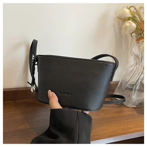 Detail of black pebbled leather crossbody bag featuring embossed FASHION lettering