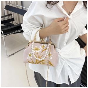 Detail of vintage pink satin handbag with lily embroidery and pearl handle